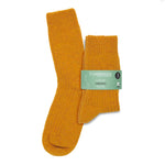 A pair of mustard yellow ribbed merino wool boot socks in a printed merino paper band on a white background.