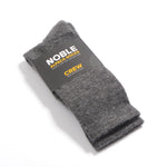 Grey Noble alpaca crew socks folded in a Noble paper band