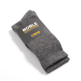 Grey Noble alpaca crew socks folded in a Noble paper band